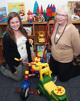 Librarian Mary Hubbard with her student assistant in front of the toy lending collection